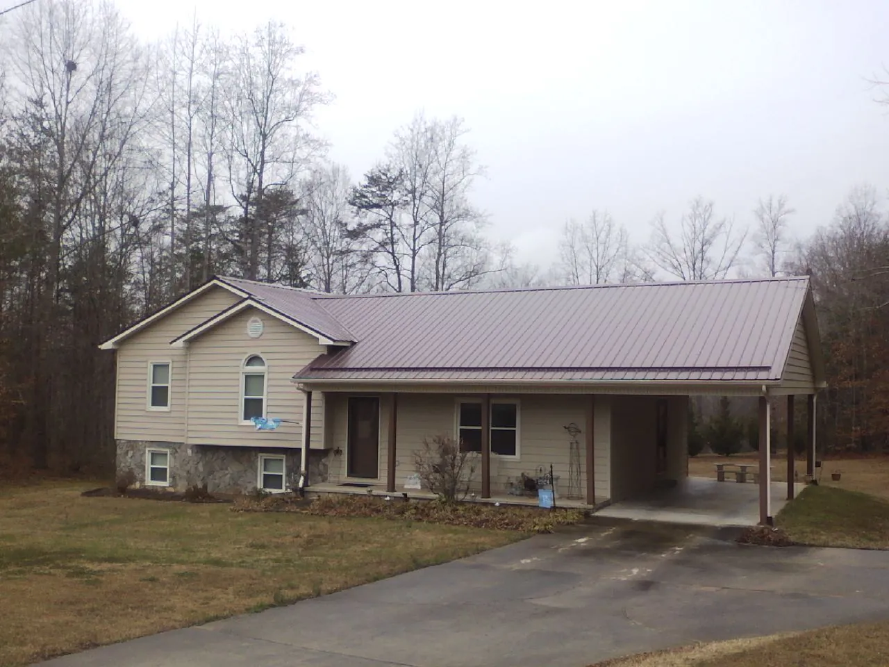 Burgundy metal roof on a tan split level home with an attached carport in Doty