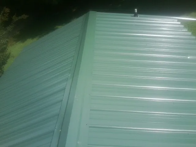 New green metal panels meeting at the ridge of a roof — Flat Roof Repair work by our crew in Doty