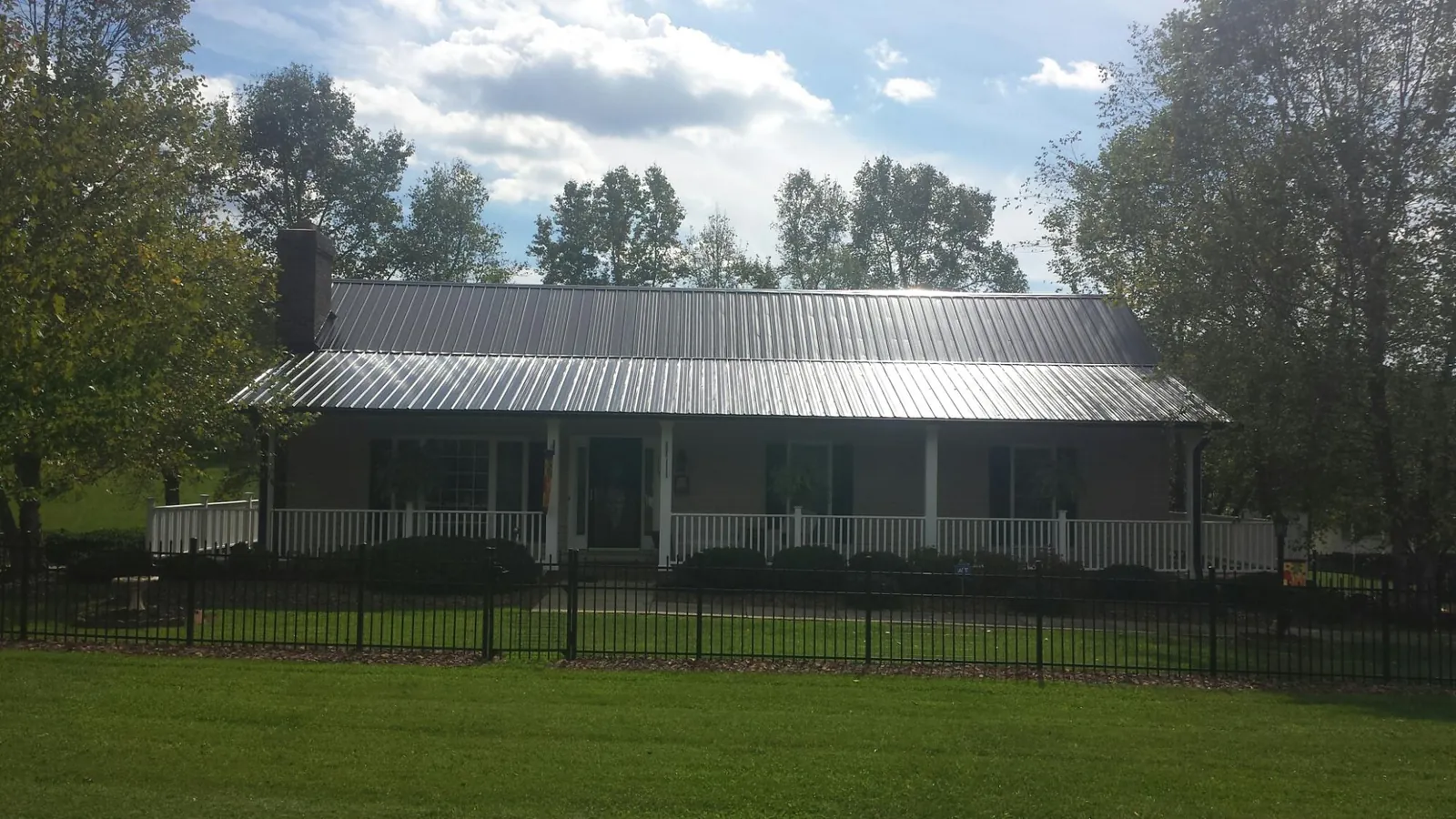 Gray metal roof on a brick ranch with a full width front porch — Gutter Guard Installation work by our crew in Doty