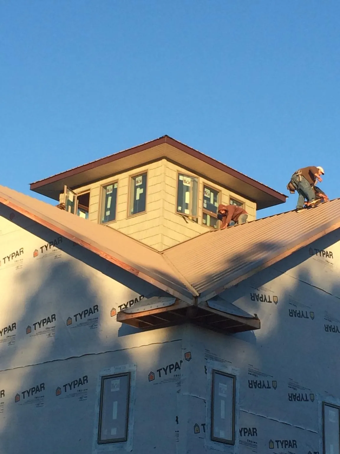Roofers working around a rooftop cupola on a new metal roof at sunset — Roof Waterproofing in Doty by Roofing Brothers